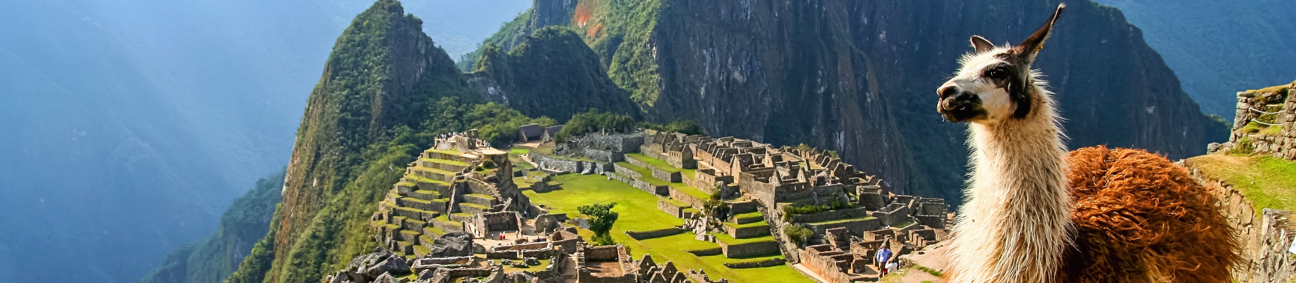Panoramic view of Machu Picchu surrounded by lush Andean mountains.